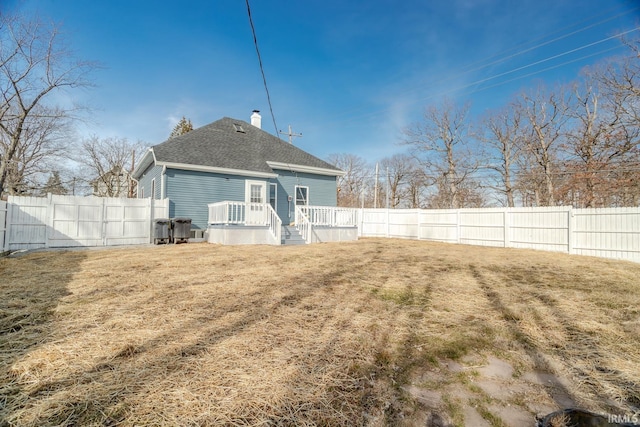 rear view of property with a fenced backyard, roof with shingles, and a chimney