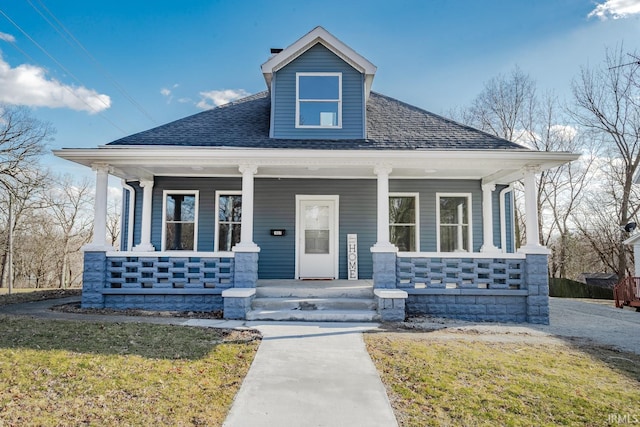 bungalow with covered porch and a shingled roof