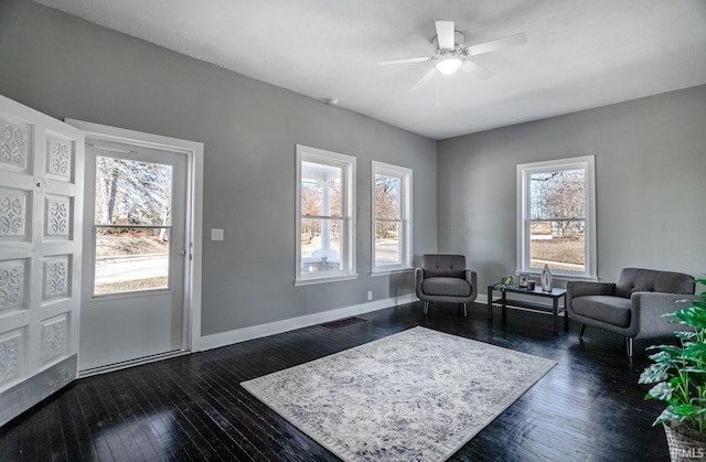 living room with dark wood-style floors, visible vents, ceiling fan, and baseboards