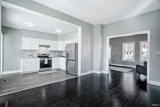 kitchen featuring under cabinet range hood, open floor plan, appliances with stainless steel finishes, white cabinets, and baseboards