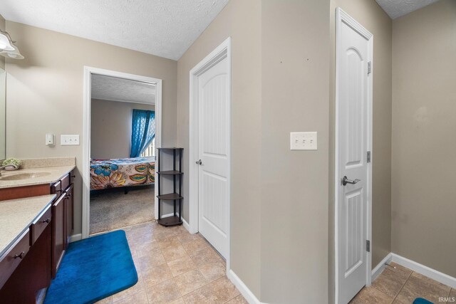 bathroom with a textured ceiling, vanity, ensuite bathroom, and baseboards