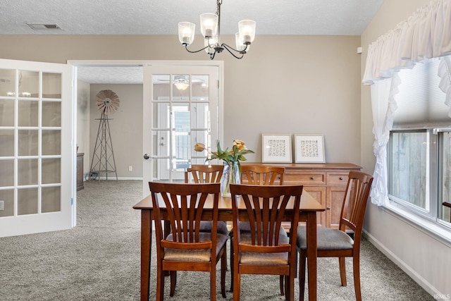 carpeted dining room featuring visible vents, an inviting chandelier, a textured ceiling, and baseboards