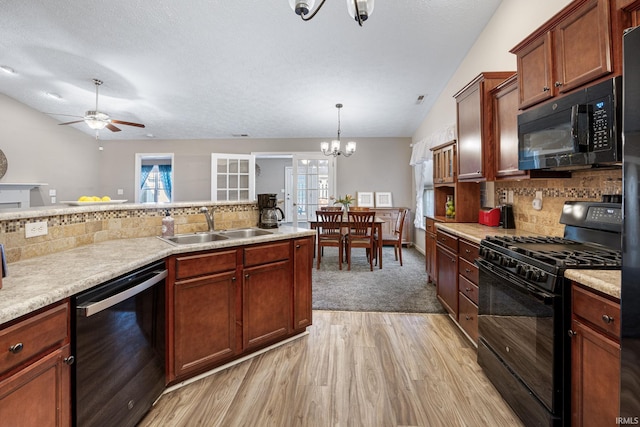 kitchen featuring lofted ceiling, a sink, black appliances, light countertops, and light wood-type flooring