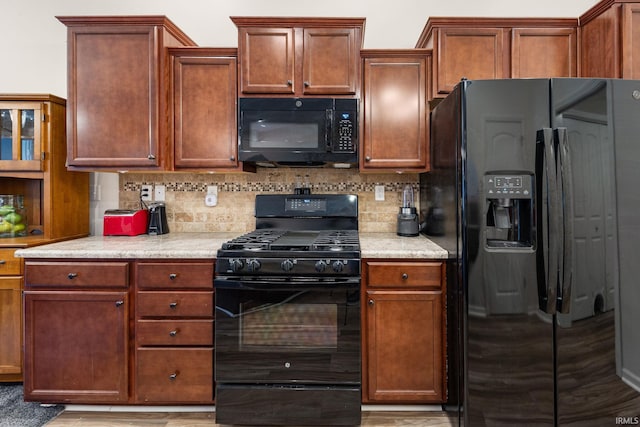 kitchen featuring decorative backsplash, black appliances, and light countertops