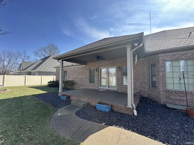 exterior space with a yard, brick siding, ceiling fan, and fence