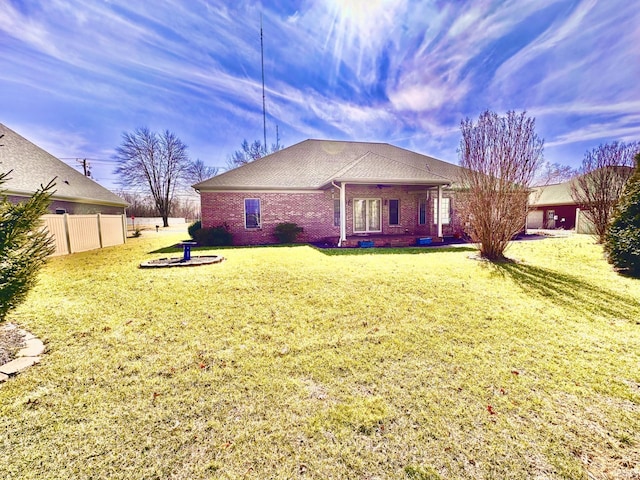 rear view of property featuring a lawn, fence, a shingled roof, crawl space, and brick siding