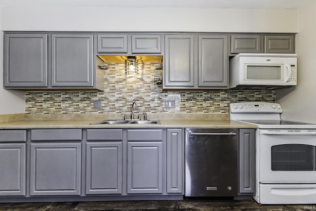 kitchen featuring a sink, white appliances, tasteful backsplash, and gray cabinetry