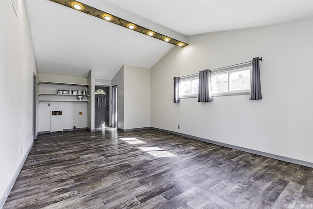 spare room featuring vaulted ceiling with beams, dark wood-type flooring, and baseboards