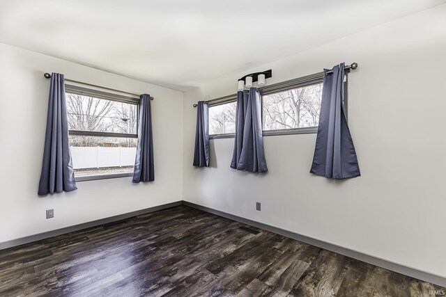 empty room with baseboards and dark wood-style floors