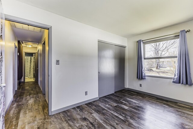 unfurnished bedroom with a closet and dark wood-style flooring