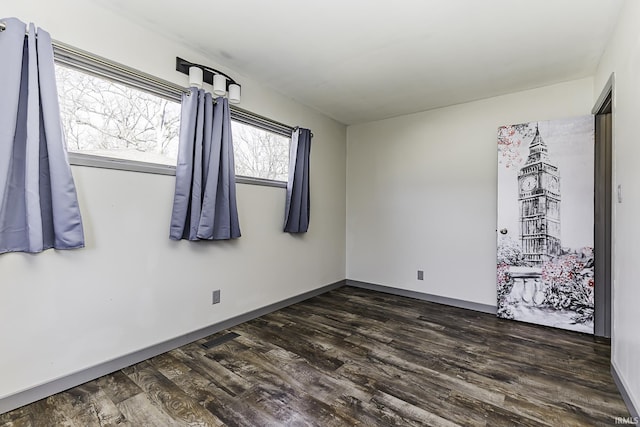 unfurnished room with baseboards and dark wood-type flooring