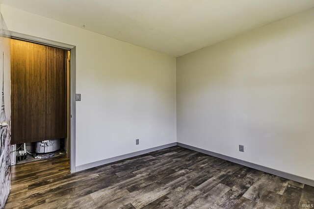 spare room featuring baseboards and dark wood-style flooring