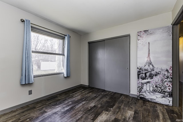 unfurnished bedroom with dark wood-type flooring, baseboards, a closet, and visible vents