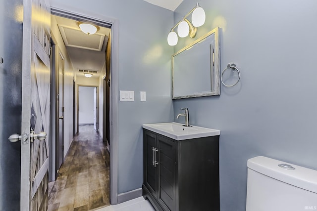 bathroom featuring visible vents, baseboards, toilet, wood finished floors, and vanity