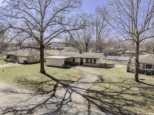 view of front of property with stone siding, a front yard, and driveway