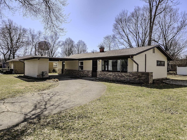 view of front of home featuring brick siding, concrete driveway, a chimney, and a front yard