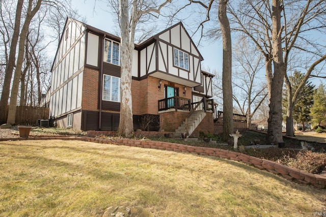 exterior space with a yard, stucco siding, stairs, central air condition unit, and brick siding