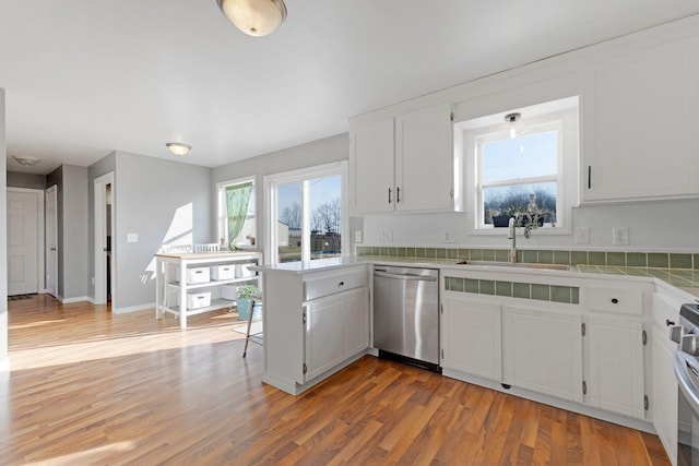 kitchen with a peninsula, white cabinets, light wood-style floors, and appliances with stainless steel finishes