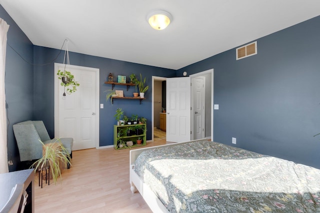 bedroom with baseboards, visible vents, and light wood-type flooring