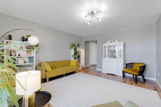 living room featuring an inviting chandelier, baseboards, and wood finished floors