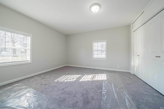 unfurnished bedroom with a closet, baseboards, and carpet flooring