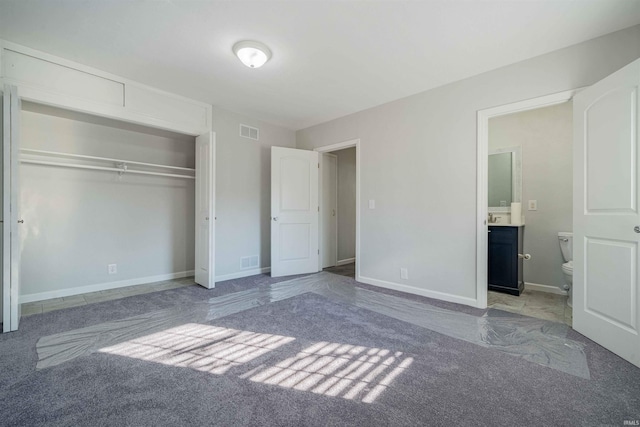 unfurnished bedroom with a closet, visible vents, ensuite bathroom, and carpet floors