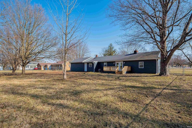 ranch-style house with a wooden deck, a chimney, a front lawn, and fence