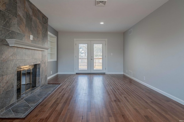 unfurnished living room with visible vents, baseboards, dark wood finished floors, and a fireplace