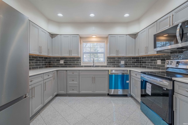 kitchen featuring recessed lighting, gray cabinets, appliances with stainless steel finishes, and a sink