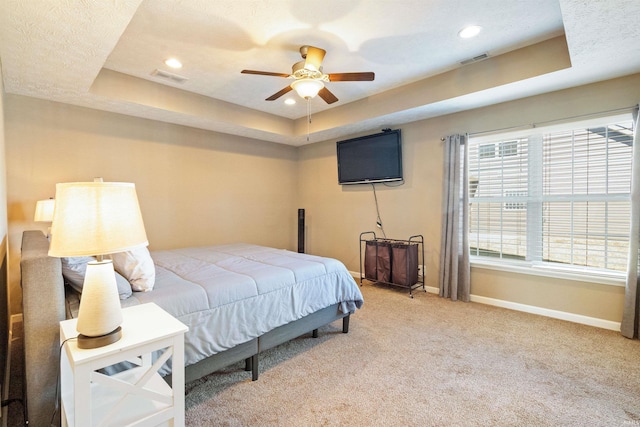 bedroom featuring a tray ceiling, baseboards, light carpet, and visible vents