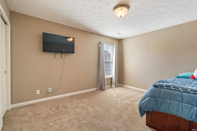 bedroom with a textured ceiling, baseboards, and carpet floors