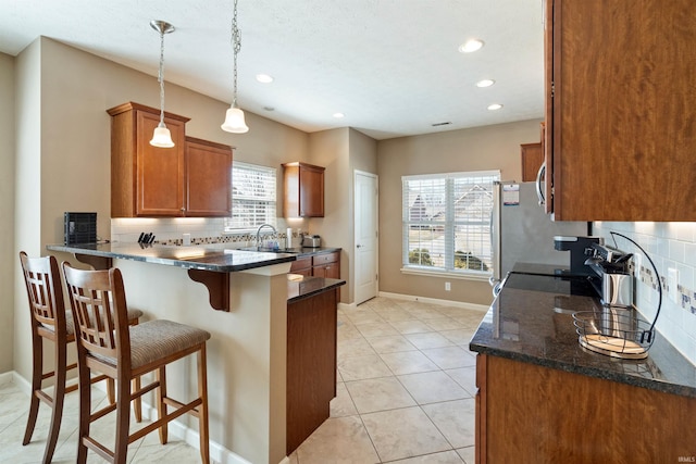 kitchen with brown cabinets, a sink, a kitchen breakfast bar, a peninsula, and appliances with stainless steel finishes