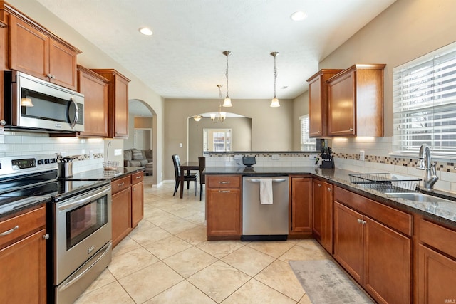 kitchen featuring light tile patterned floors, brown cabinets, appliances with stainless steel finishes, and a sink