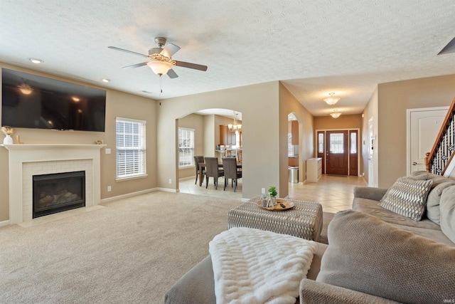 living room featuring a textured ceiling, a brick fireplace, arched walkways, and light carpet