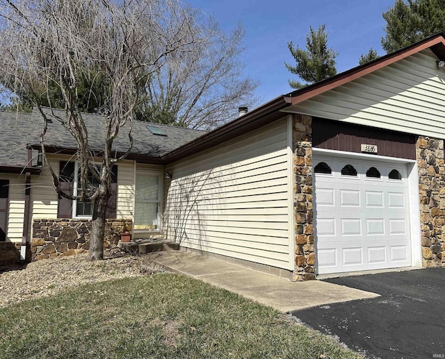 view of side of home featuring a garage, stone siding, and a shingled roof