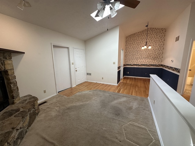 unfurnished living room featuring visible vents, a stone fireplace, carpet floors, and vaulted ceiling