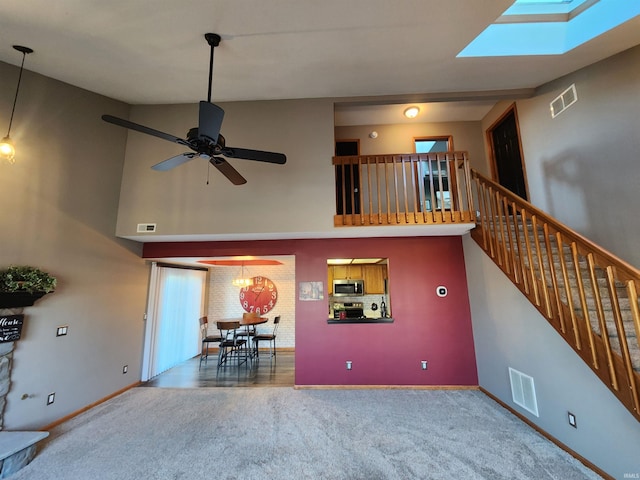 unfurnished living room featuring visible vents, a towering ceiling, and carpet floors