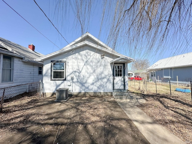 rear view of house featuring central AC unit and fence