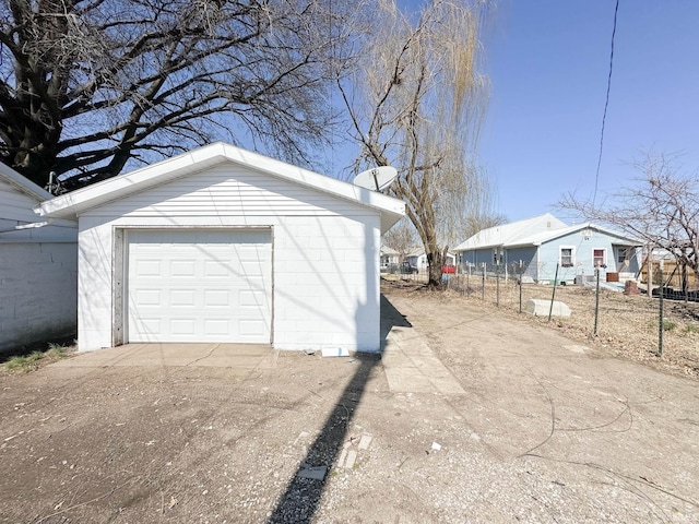 detached garage featuring fence, a residential view, and driveway