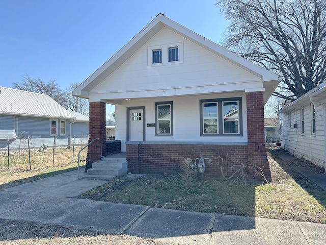 bungalow featuring brick siding, a porch, and fence