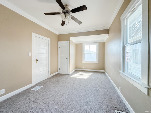 spare room featuring visible vents, carpet floors, crown molding, baseboards, and ceiling fan