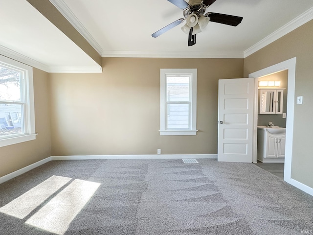 carpeted spare room featuring a sink, baseboards, ornamental molding, and a ceiling fan