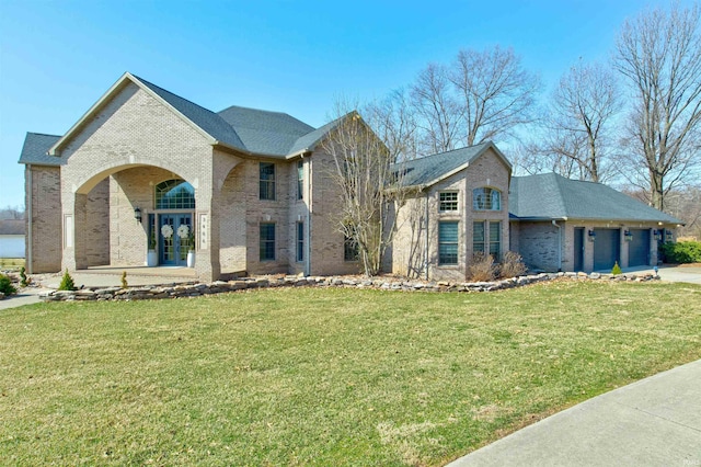 view of front of house featuring brick siding, an attached garage, driveway, and a front lawn