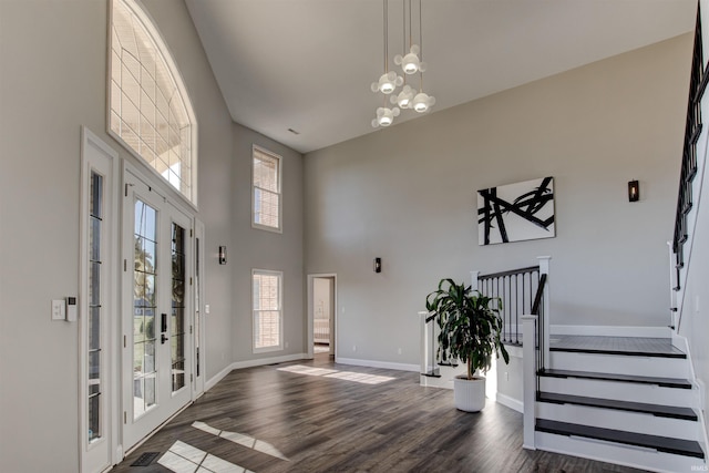 foyer with dark wood finished floors, a high ceiling, a healthy amount of sunlight, and baseboards