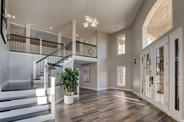 foyer entrance with baseboards, stairs, french doors, wood finished floors, and a notable chandelier