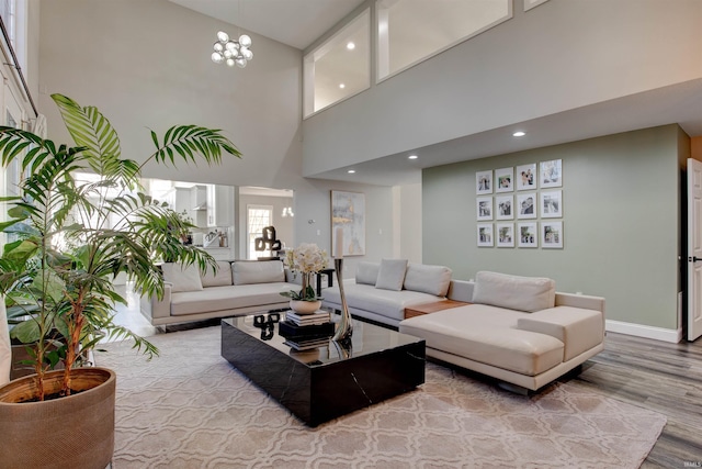 living area featuring baseboards, a chandelier, recessed lighting, a towering ceiling, and wood finished floors