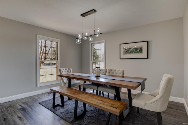 dining space featuring dark wood finished floors, an inviting chandelier, and baseboards