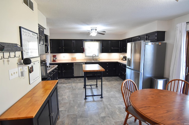 kitchen with visible vents, wooden counters, appliances with stainless steel finishes, dark cabinetry, and a sink