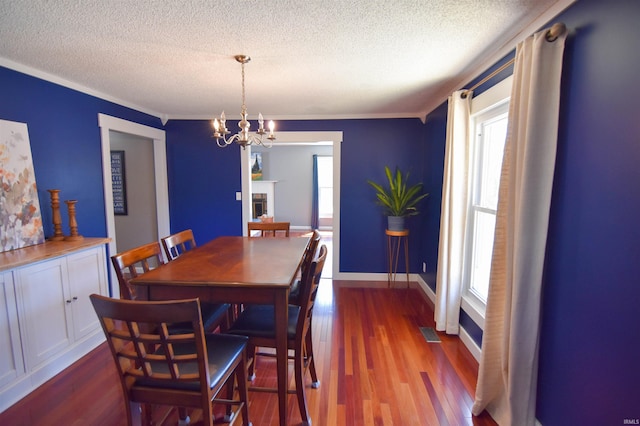 dining room with visible vents, baseboards, a fireplace, a textured ceiling, and dark wood-style flooring