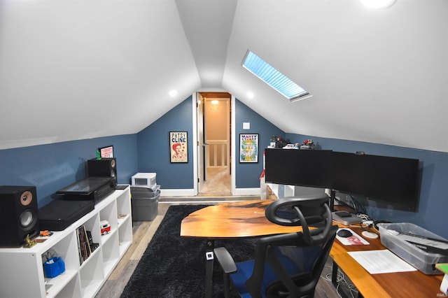 home office with lofted ceiling with skylight, baseboards, and wood finished floors